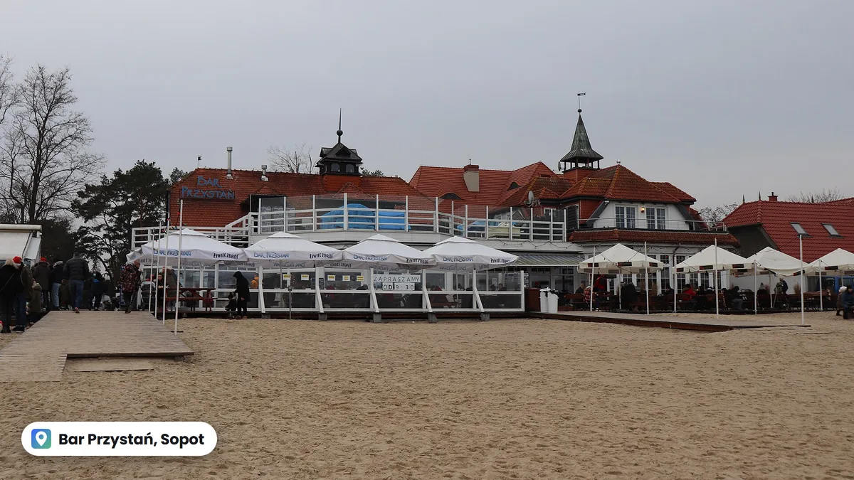 Bar Przystań na plaży w Sopocie, budynek z czerwonymi dachami i parasole przed wejściem