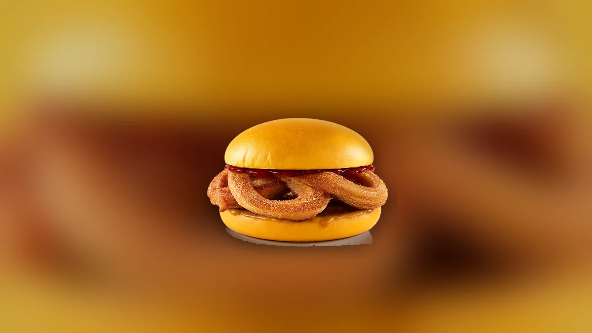 Churros Burger z KFC: żółta bułka, w środku churros obsypane cukrem z cynamonem, sos truskawkowy i krówkowy