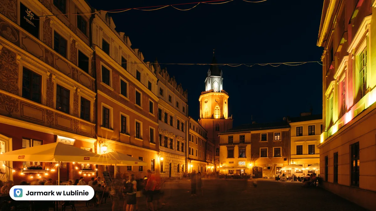 Rynek Starego Miasta w Lublinie wieczorem: oświetlone kamienice, ogródki restauracji i wieża w tle