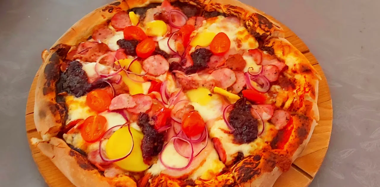 Pizza z kiełbasą, pomidorkami i cebulą w barze Pan Wurst
