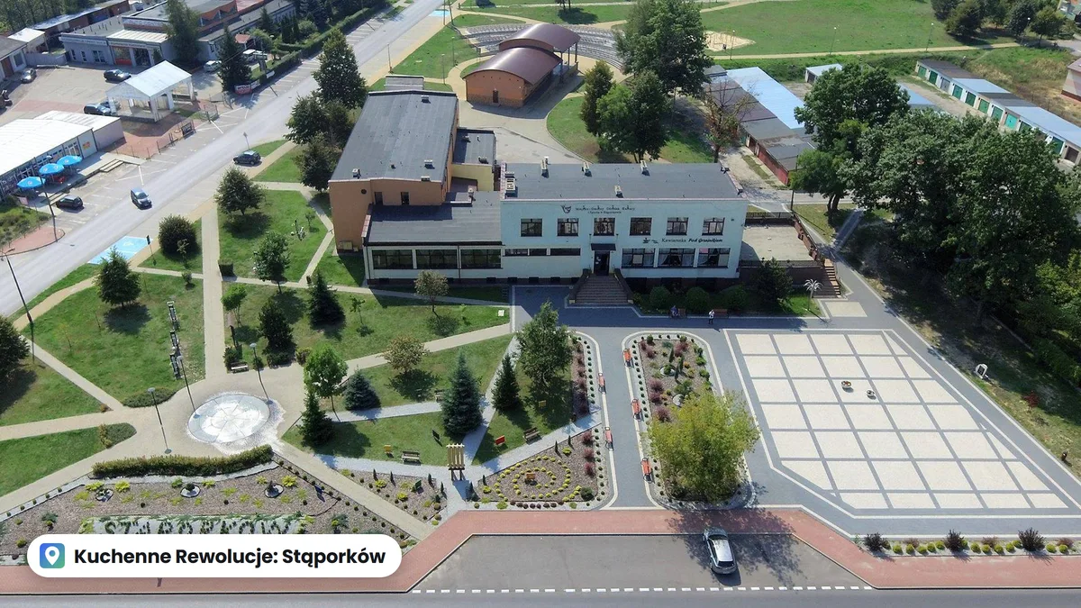 Budynek domu kultury w Stąporkowie z lotu ptaka, przed nim skwer z rabatami i plac