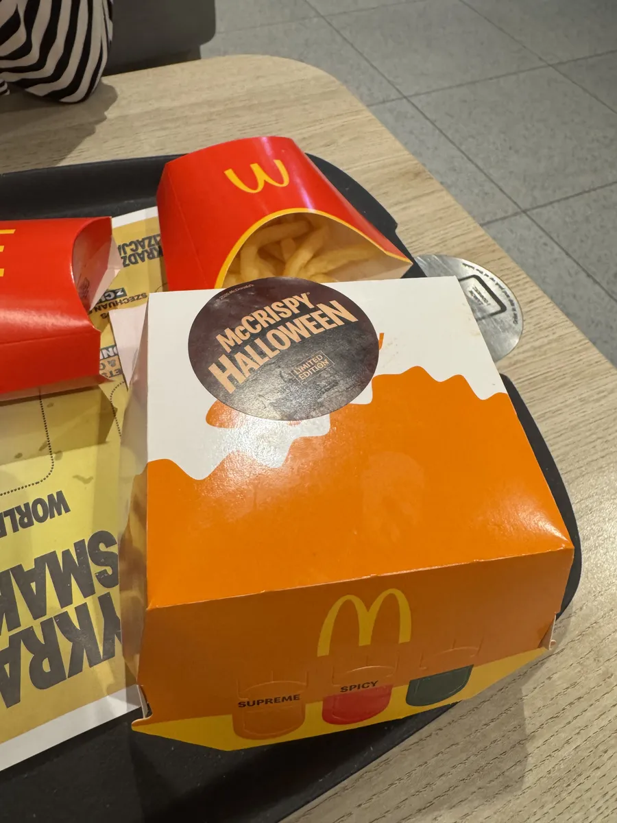 Pomarańczowe pudełko McCrispy Halloween z naklejką Limited Edition na tacy obok frytek