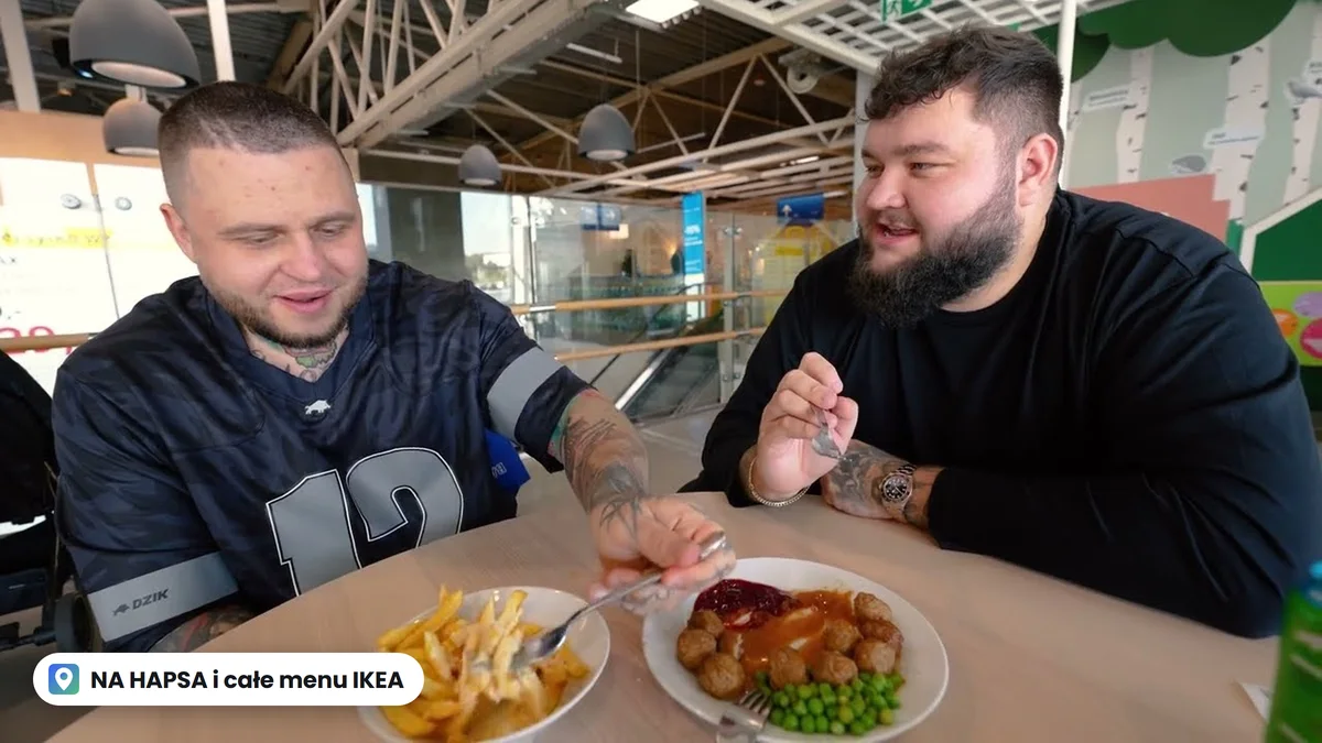 Dwóch twórców NA HAPSA przy stoliku w restauracji IKEA, przed nimi frytki i klopsiki z sosem, borówką i groszkiem