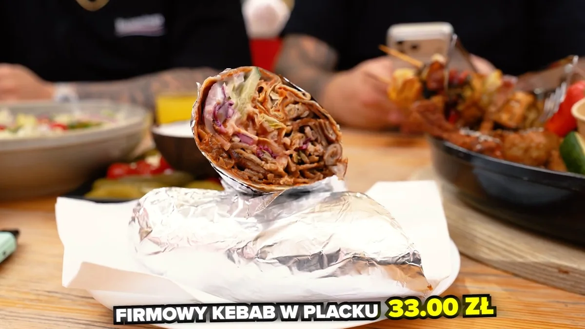 Firmowy kebab w placku tureckim z Planety Lewobrzeże, przekrojony, na folii