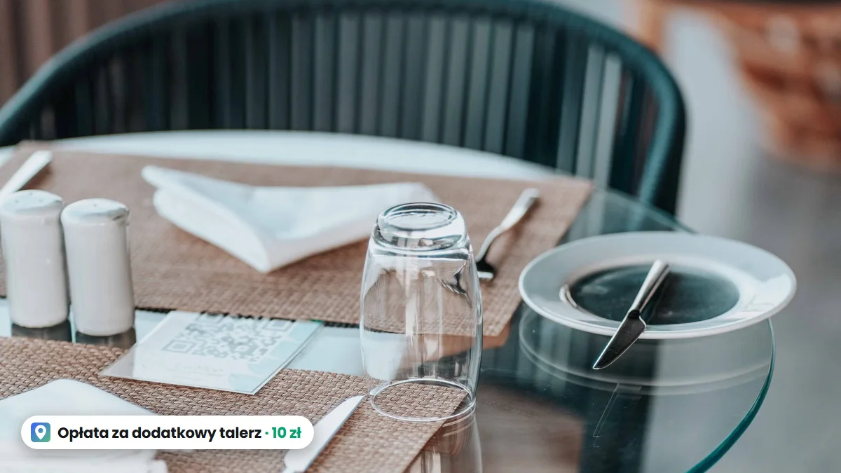 Nakrycie w restauracji: pusty talerz, nóż, szklanka i serwetka na szklanym stoliku