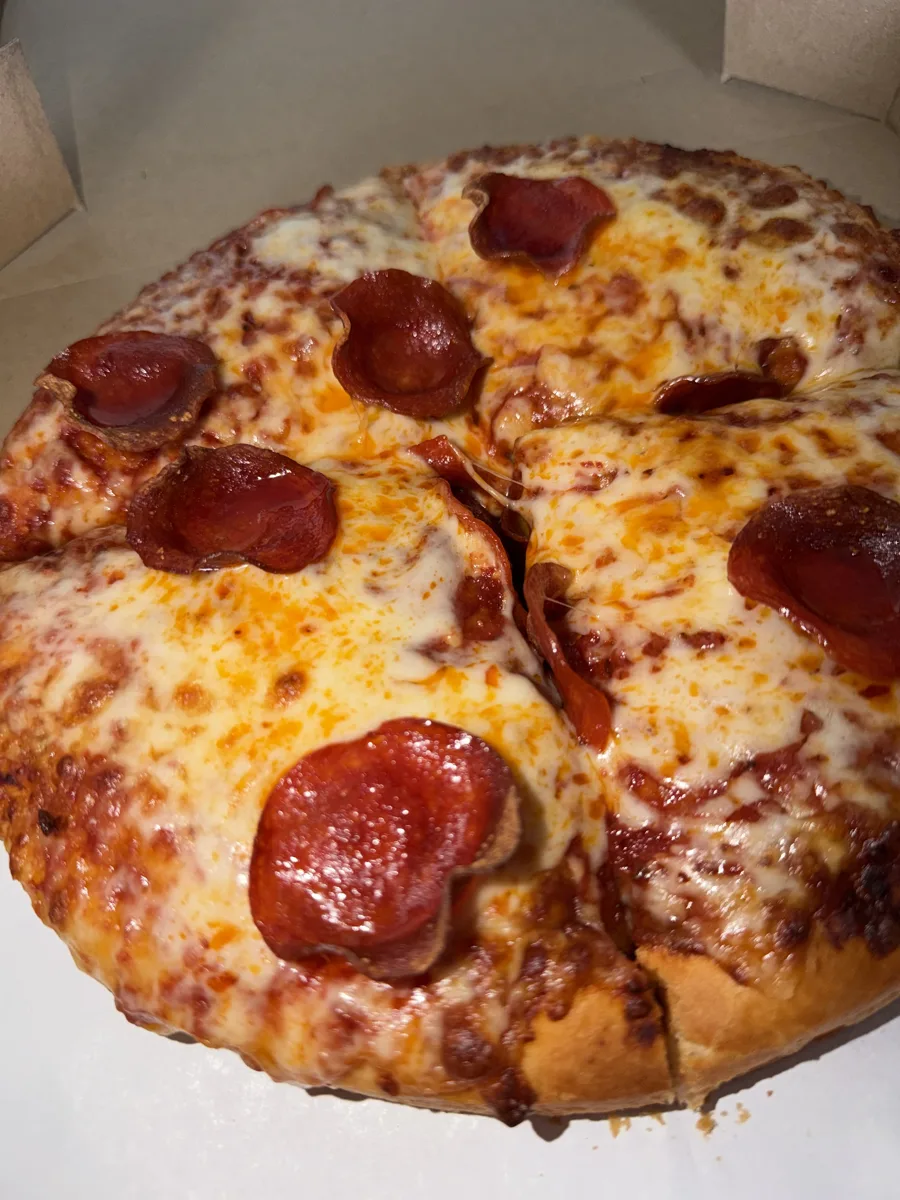 Zbliżenie na pizzę Fat Peppa: roztopiony ser i zwinięte plastry pepperoni