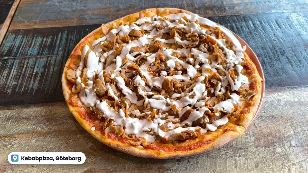 Szwedzka kebabpizza z mięsem kebab i białym sosem na drewnianym stole