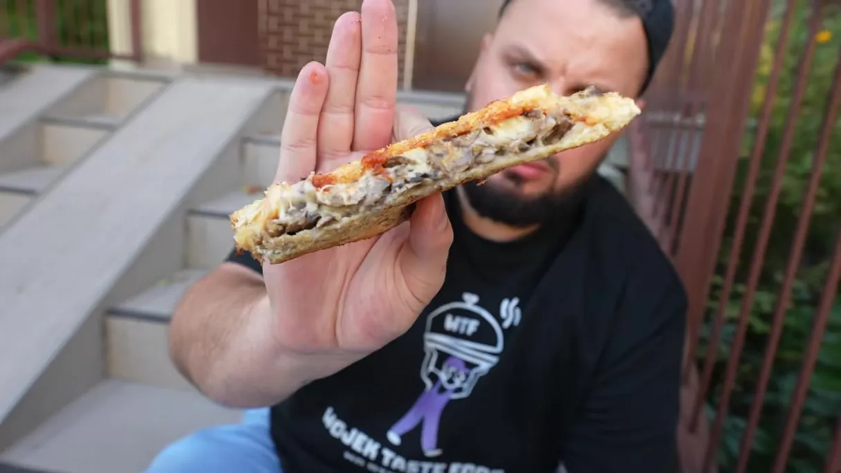 Wojek pokazuje do kamery tost z serem i pieczarkami z Zbyszko Bar we Wrocławiu