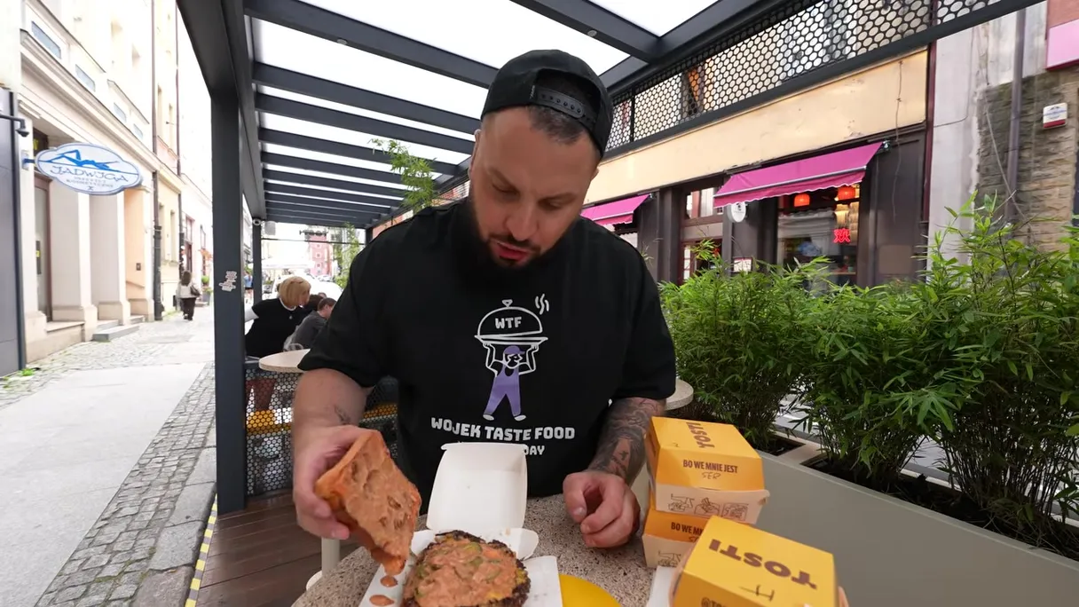 Wojek przy stoliku przed lokalem Tosti we Wrocławiu z zamówieniem w pudełkach i torbie